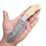 Damascus gut hook hunting knife with ivory-colored handle, silver bolster and patterned blade