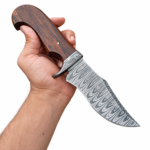 Brown handle Bowie knife held in a hand, showing a broad gray patterned blade, matching curved guard, hooked grain-look grip, and silver-tone pin.