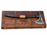 Norse Rune Viking Axe with blackened textured metal head, pointed projection, curved silver-edged blade, rune-style markings and dark wood-look handle with orange symbols.