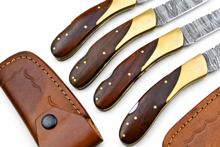 Four Damascus Folding Pocket Knives with wood-grain handles, gold-tone bolsters and brown stitched sheaths