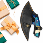 Two-tone Ulu knife handle with blue-green wood-grain appearance, cream-colored inlay, finger ring and mosaic-style pin