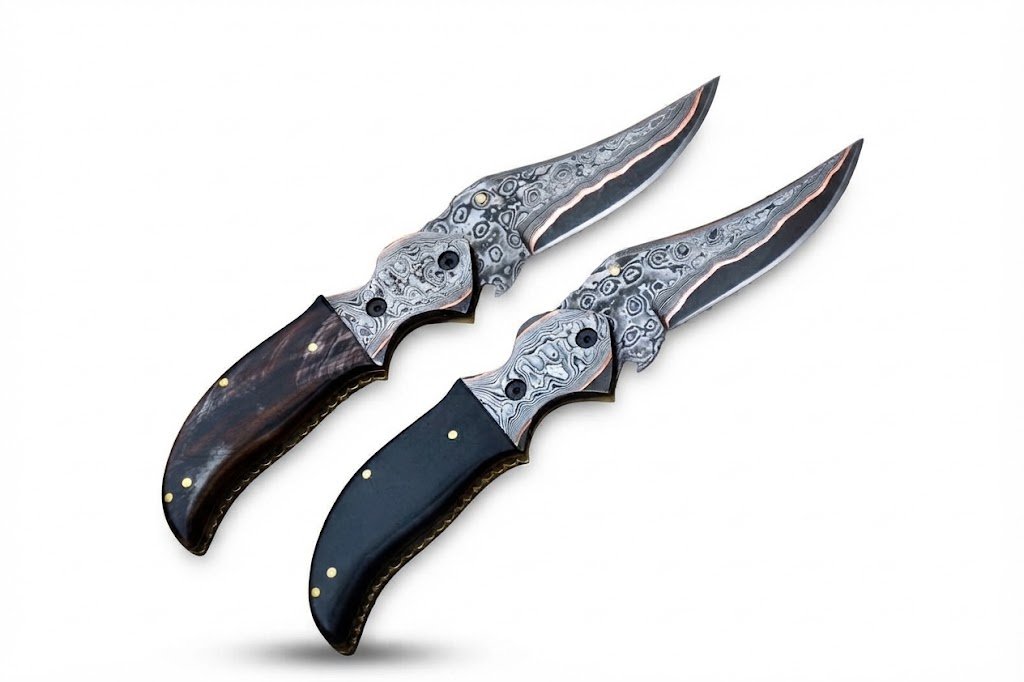 636ea117-edf9-44af-9a8d-faf9963a8a02 Two Damascus pattern folding knives with curved silver-gray patterned blades, copper-colored accents, ornate pivot fittings, and brown and black handles