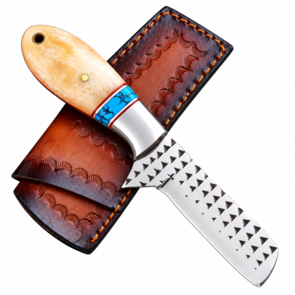 Cream handle cowboy knife with a turquoise-colored band and triangular rasp-style blade texture resting on a brown decorated sheath with orange stitching.