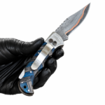 Blue Carbon Damascus Folding Knife shown open with silver-gray patterned blade, copper-colored edge accent, polished bolster and blue-black woven-style handle