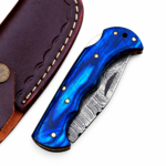 Blue Damascus Pattern Folding Knife shown open with a curved silver-gray patterned blade, electric-blue contoured handle and metallic decorative pins