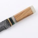 Damascus Utility Knife featuring a silver-gray patterned blade, curved pointed tip, wooden-look handle and decorative green accents.
