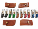 Damascus Pattern Knife collection showing ten fixed-blade knives with silver-gray patterned blades, black, brown, red, blue and green handles, and brown sheaths.