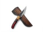 Red and Black Wood Handle Fixed Blade Hunting Knife with polished and dark two-tone blade beside a brown basketweave-style sheath