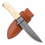 Cream handle hunting knife with black-and-silver Damascus-style patterned blade, gold-colored handle pins, small guard, and pointed blade
