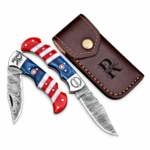 Open red white and blue folding knife with a patterned blade, star handle detail and monogrammed silver-tone bolster resting on a brown stitched pouch.
