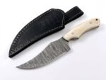 Ivory Handle Curved Skinner Knife with silver-gray Damascus-style patterned blade, cream-colored contoured handle and black stitched leather-style sheath.