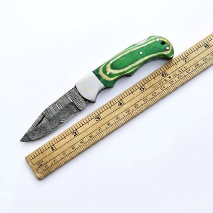 Damascus Steel Folding Pocket Knife with patterned curved blade, green wood-style handle, silver-toned bolster and decorative metal pins on white background.