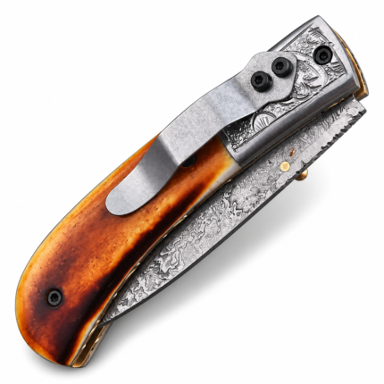 Amber-tone Damascus folding knife with a copper-colored wave along its patterned silver-gray blade, honey-brown handle, ornate silver bolster and metal pocket clip.