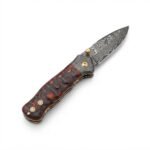 Wavy Handle Damascus Folding Knife with curved patterned blade, black and copper-brown sculpted handle, ornate silver pivot and brown snap-closure pouch.
