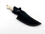 Ivory Handle Curved Skinner Knife with silver-gray Damascus-style patterned blade, cream-colored contoured handle and black stitched leather-style sheath.