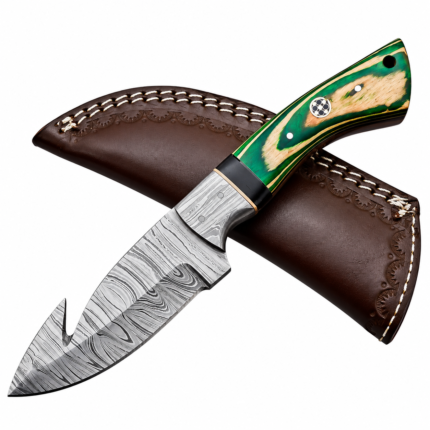 Green handle gut hook knife with a Damascus-style blade and decorative pin resting across a brown sheath with pale stitching.