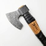 Damascus Pattern Bearded Hatchet with silver-grey curved axe head, striped brown wood-look handle, black wrapped grip and V-shaped handle marking