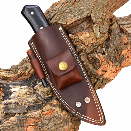 Fixed blade hunting knife with black handle stored in brown leather-style sheath with snap-button accessory pouch on tree bark