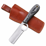 Premium cowboy knife with straight satin-finished blade, circular blade opening, textured black wood-grain handle, silver metal pins, and gold-tone lanyard hole
