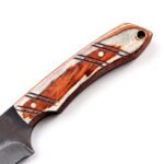 Compact Curved Skinner Knife with broad two-tone blade, brown and cream wood-grain-style handle and tan stitched belt sheath with snap closure.