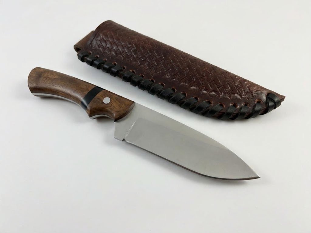 WhatsApp Image 2026-10-30 at 2.57.43 AM Wooden Handle Hunting Knife with broad satin-finished silver blade, curved brown wood-grain handle and dark brown embossed sheath with black edge lacing.