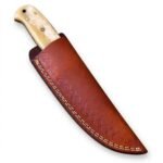 Cream Handle Damascus Hunting Knife with curved silver patterned blade, decorative metal bolster, pale ivory-look handle and reddish-brown stitched sheath