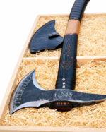 Norse Rune Viking Axe with blackened textured metal head, pointed projection, curved silver-edged blade, rune-style markings and dark wood-look handle with orange symbols.