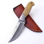 Cream Handle Damascus Hunting Knife with curved silver patterned blade, decorative metal bolster, pale ivory-look handle and reddish-brown stitched sheath