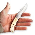 Cream Handle Fixed Blade Knife with polished pointed blade, silver bolster, decorative handle pins and lanyard hole displayed in an open hand