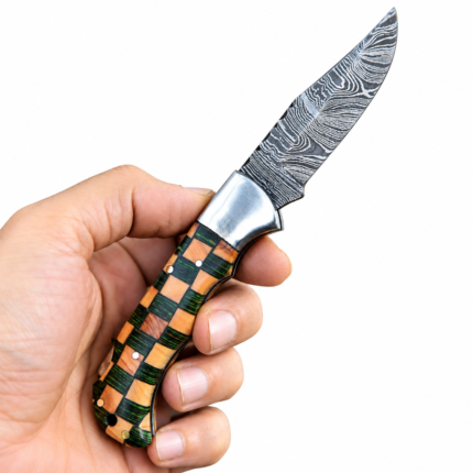 Open green handle folding knife with tan block accents, a Damascus-style blade, and silver-tone bolster resting on a stitched brown pouch.
