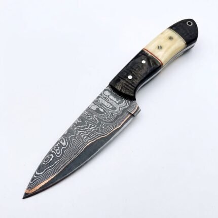 Damascus Pattern Fixed Blade Knife with pointed silver-gray patterned blade, black and ivory-style handle, decorative pins and metal-lined lanyard hole.
