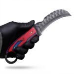 Red Blue Handle Karambit Knife with black curved claw blade, textured metallic finish, red-and-blue handle, gold-colored pins and circular finger ring