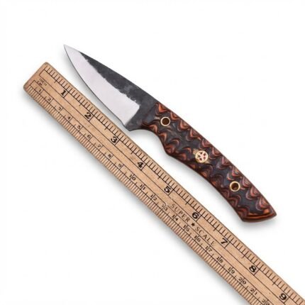 Patterned handle skinner knife with dark and silver pointed blade, brown-and-black decorative grip, mosaic-style pin and black sheath with tan stitching.