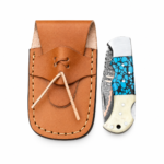 Open turquoise blue folding knife with a blue-and-black patterned handle, cream rear section, silver-tone bolster, and patterned blade with a copper-tone stripe.
