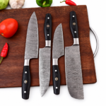 Black textured chef knife handle featuring silver-colored pins and a decorative gold-and-black mosaic accent
