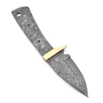 Raindrop-pattern knife blank with guard in gold tone, exposed full tang, two small holes, and a larger rear opening beside an inch-and-centimeter ruler