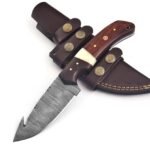 Damascus gut hook hunting knife with patterned curved blade, brown and cream handle, mosaic pin and dark brown stitched sheath with star-shaped metal decorations.