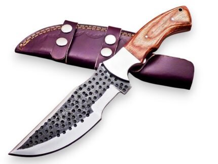 Hammered Pattern Hunting Knife with dark circular blade detailing, silver bevel, light brown wood-grain-look handle and burgundy double-strap sheath.