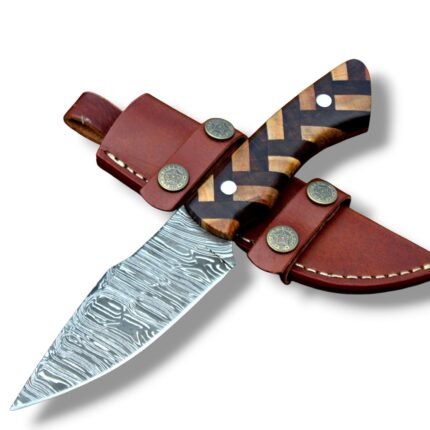 Geometric handle fixed blade knife with a silver-gray patterned blade and brown-and-tan grip, resting across a brown sheath with star fittings.