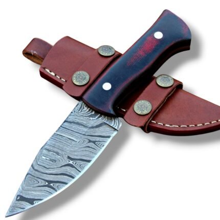 Black and burgundy knife with a silver-gray patterned fixed blade and two handle pins, resting across a brown sheath with decorative star fittings.