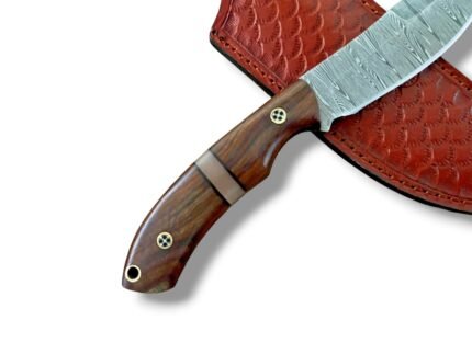 Wood Handle Damascus-Pattern Skinning Knife with curved silver-gray blade, brown contoured handle and reddish-brown embossed sheath